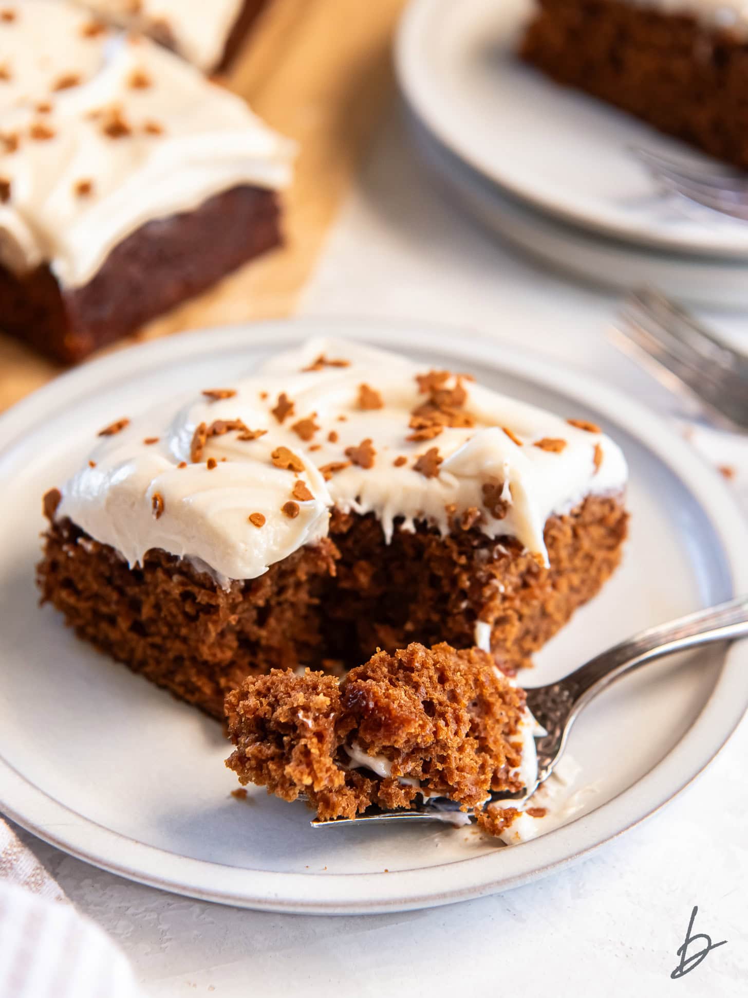 fork holding bite of gingerbread cake on plate.