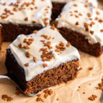 parchment paper with square slice of gingerbread sheet cake with maple frosting.