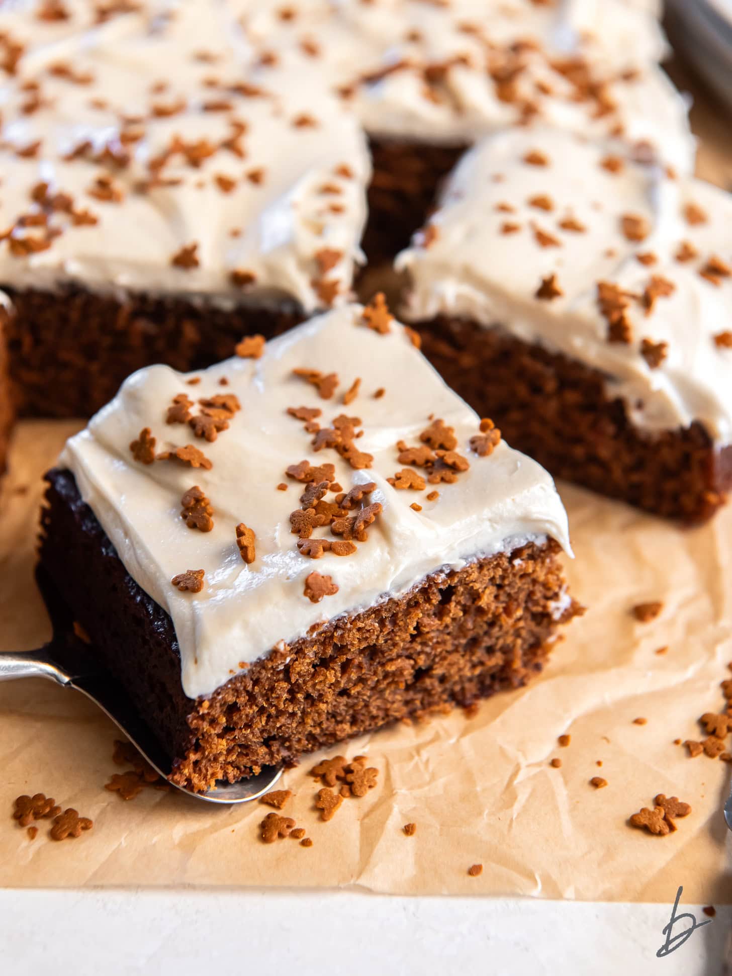 parchment paper with square slice of gingerbread sheet cake with maple frosting.