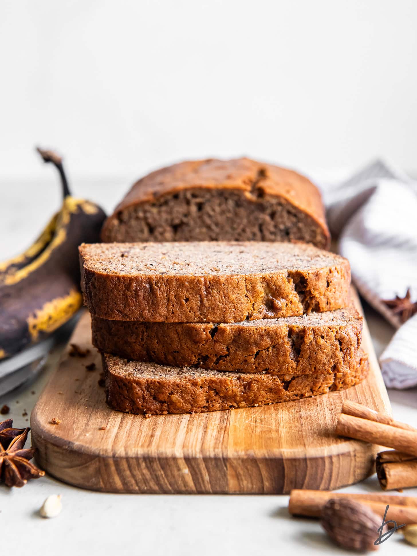 stack of three chai banana bread slices on wood cutting board.