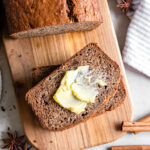 small cutting board with slice of chai banana bread with a little butter on it.