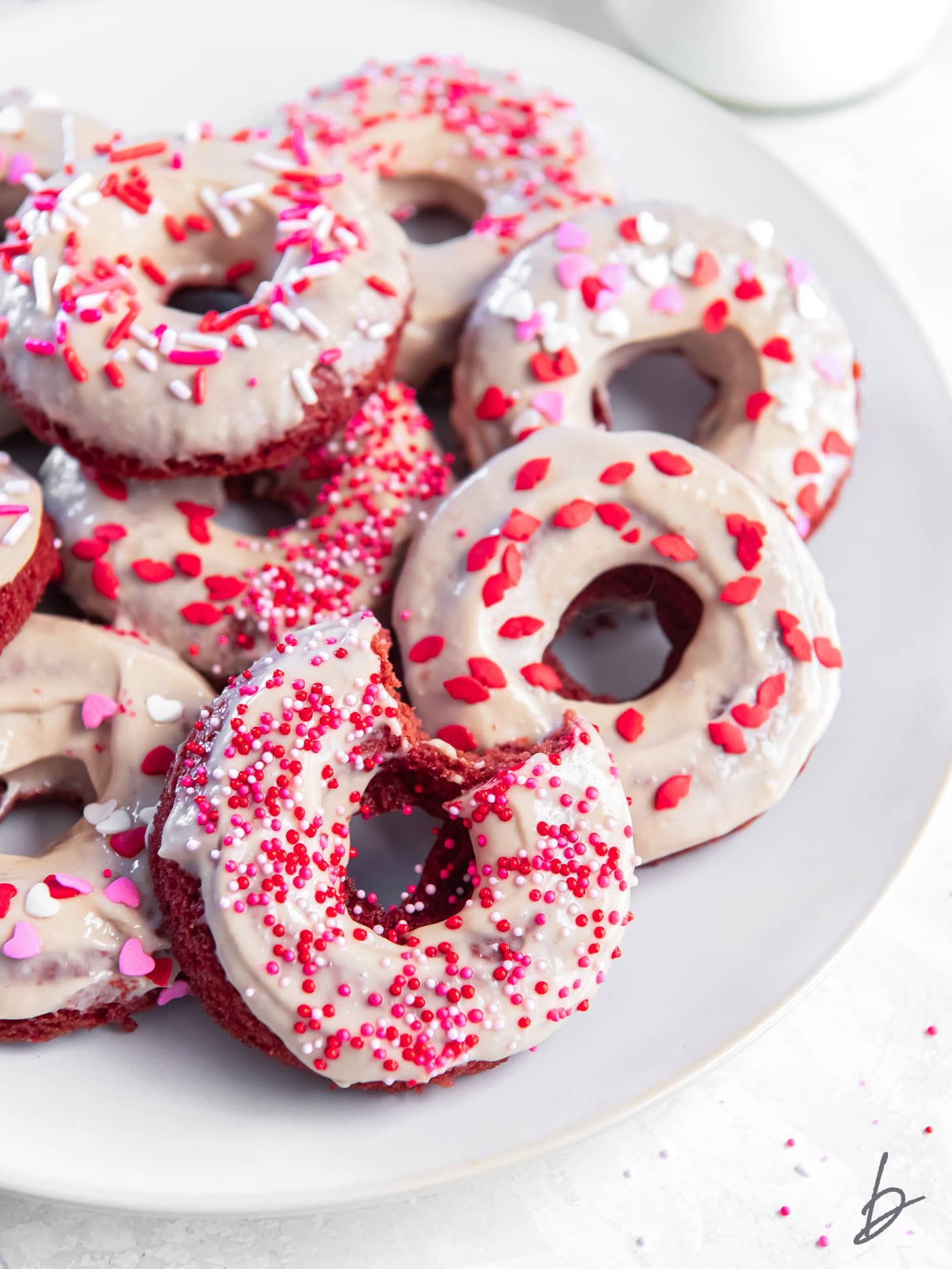 plate of red velvet donuts with cream cheese icing and sprinkles.