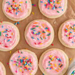 cake sugar cookies with pink frosting and sprinkles on parchment paper.