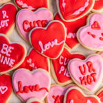 tabletop with heart shaped cookies decorated with red and pink icing.