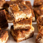 Carrot cake cheesecake bars stacked on each other.