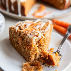 Slice of carrot cake coffee cake on a white plate with a fork.