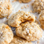 oatmeal coconut cookie with a bite taken out of it leaning on another cookie.