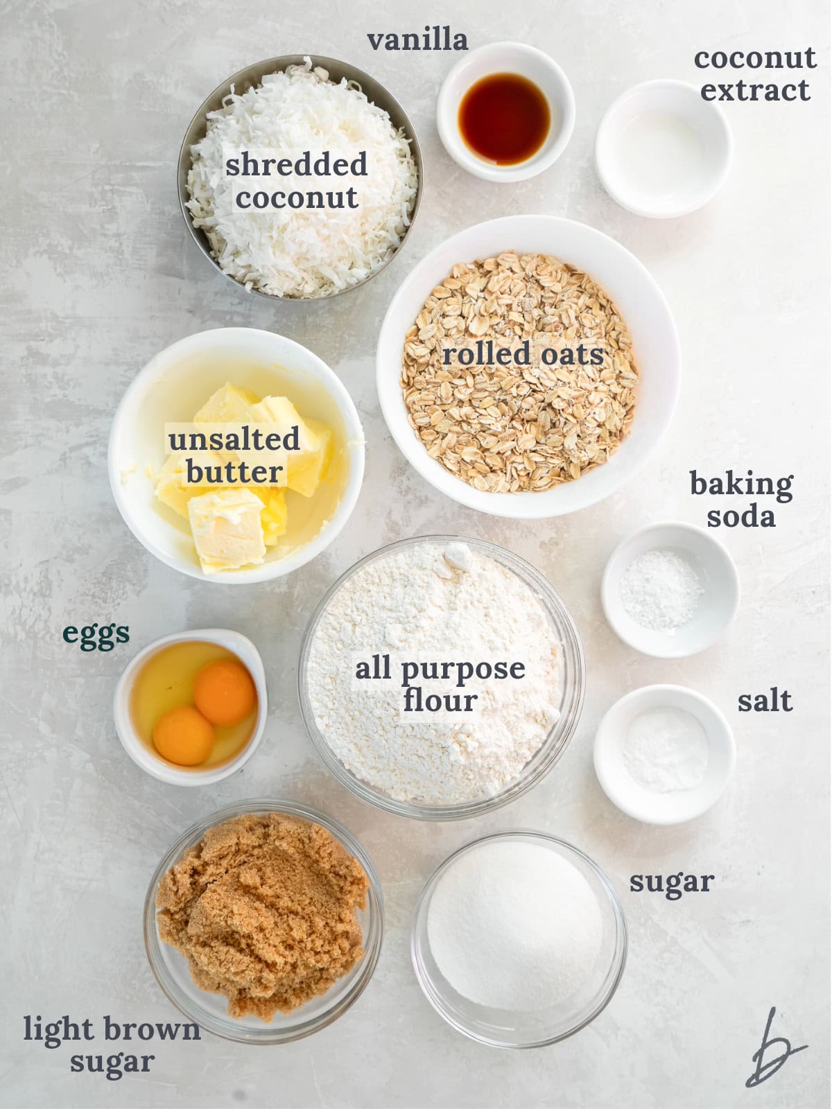 tabletop with bowls of ingredients to make oatmeal coconut cookies.