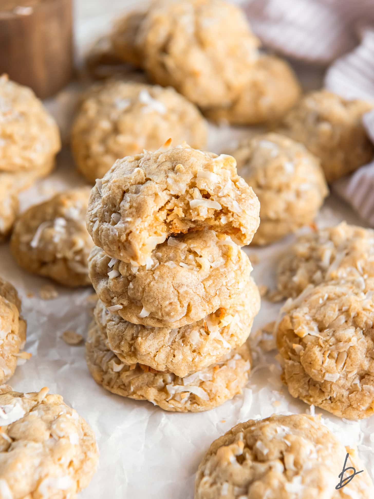 stack of thick and chewy oatmeal coconut cookies and the top cookie has a bite.