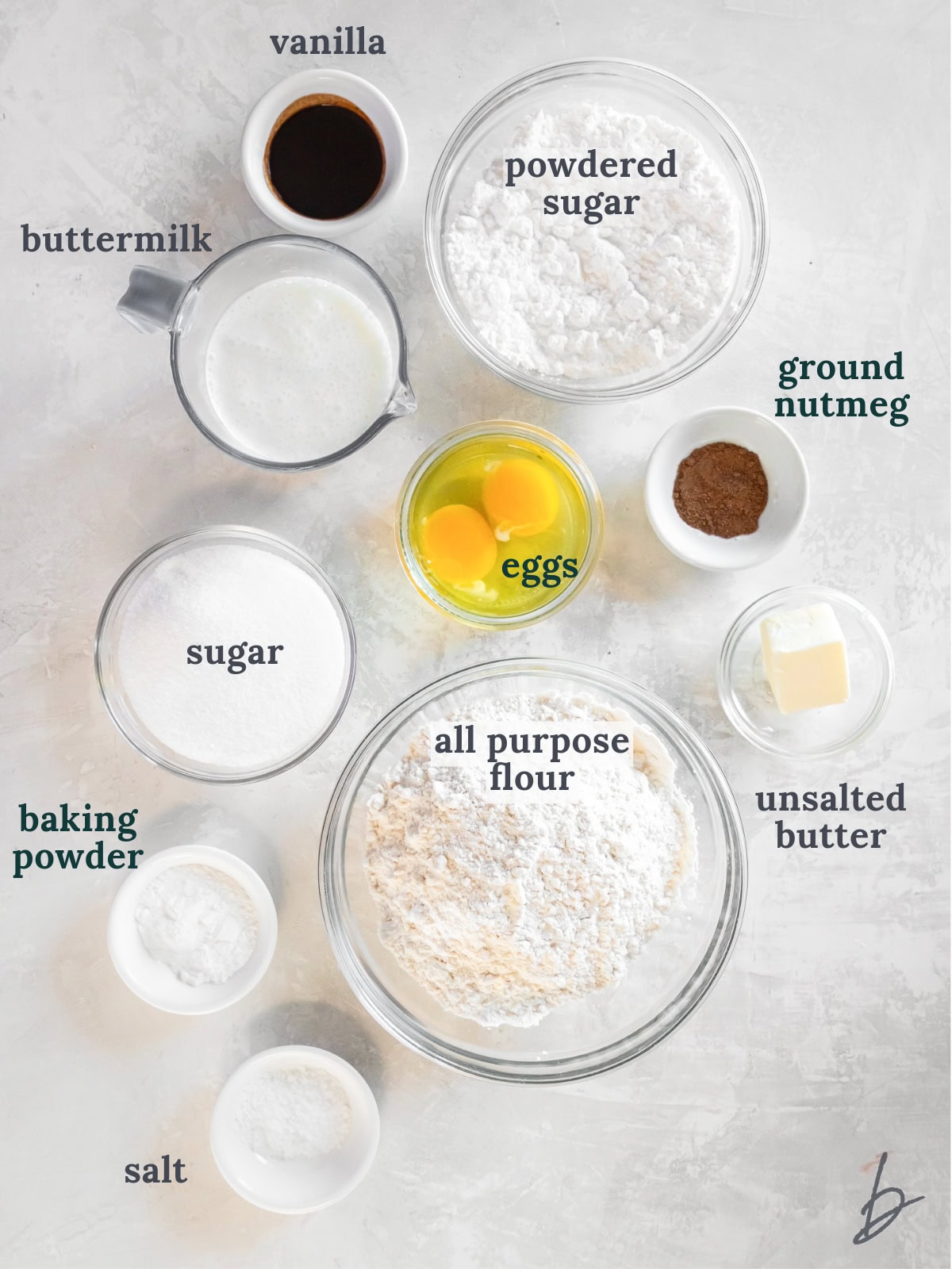 tabletop with bowls of ingredients to make powdered sugar donuts.