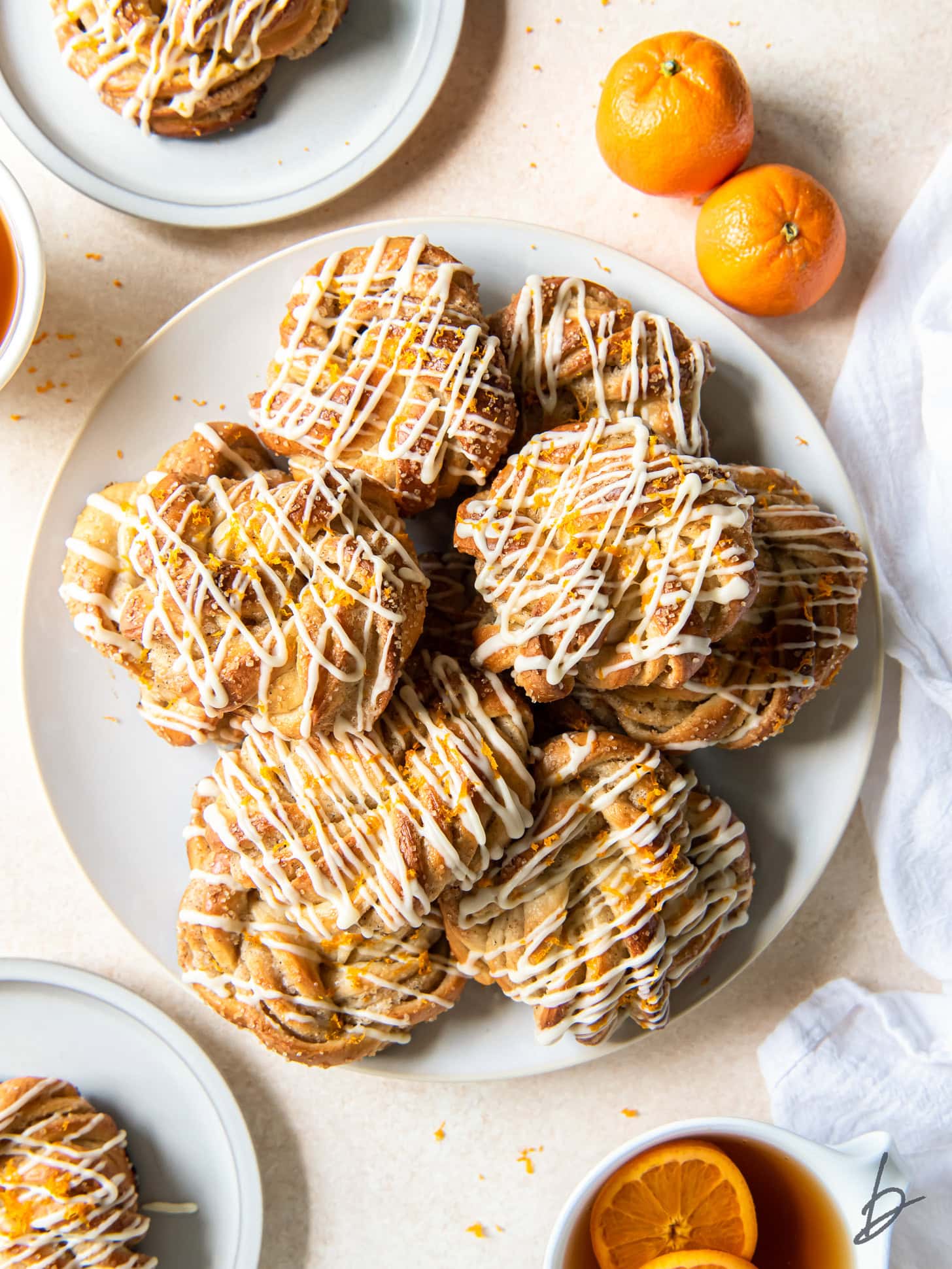 Knotted cardamom rolls with icing on a white plate.