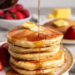 syrup poured over and dripping down stack of fluffy buttermilk pancakes.
