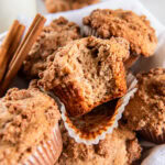 cinnamon streusel muffin with a bite taken out of it sitting on top of more muffins.