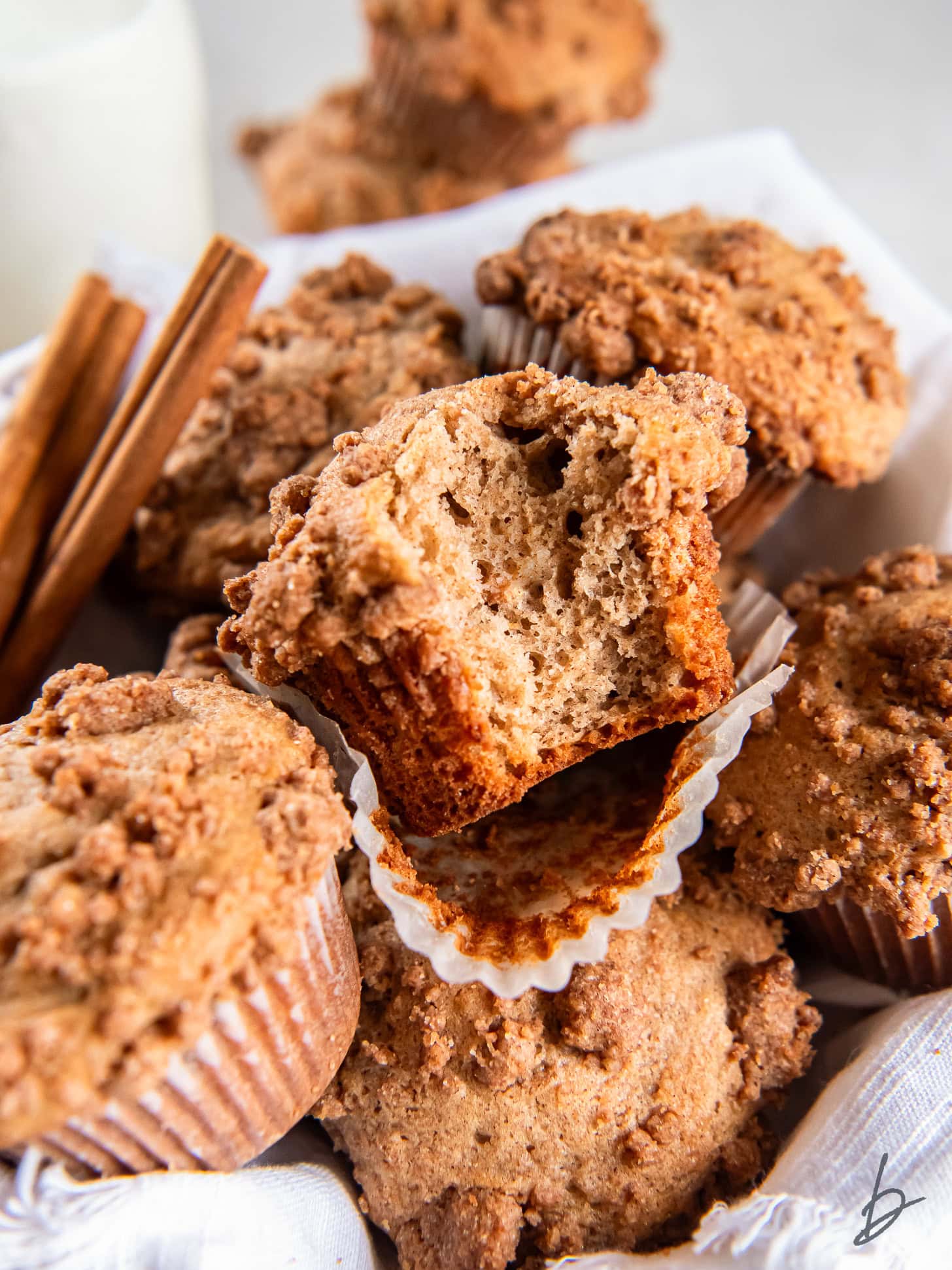 cinnamon streusel muffin with a bite taken out of it sitting on top of more muffins.
