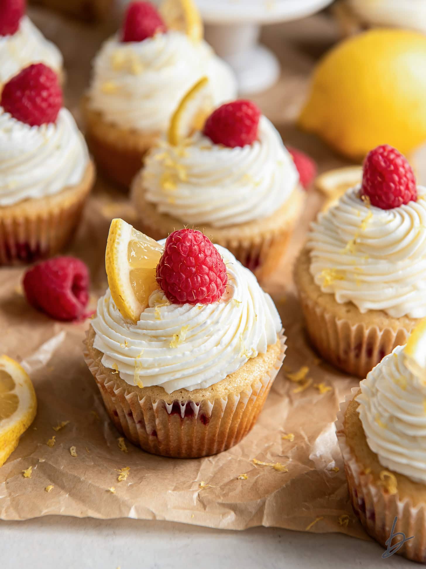 Lemon raspberry cupcakes garnished with a raspberry and slice of lemon.