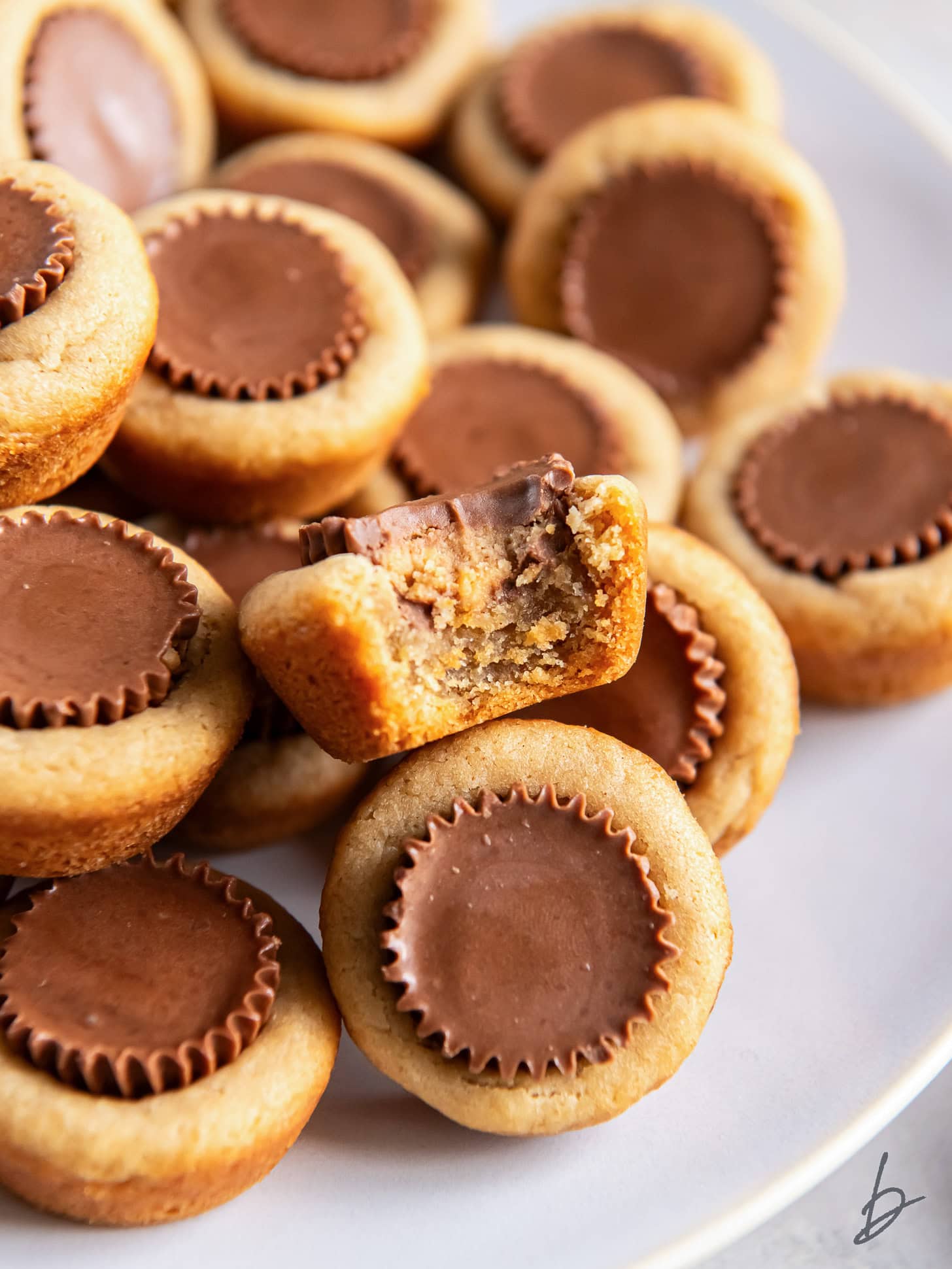 close up of peanut butter cup cookie with a bite on top of some more cookies.