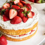 Sponge cake decorated with whipped cream and fresh strawberries.