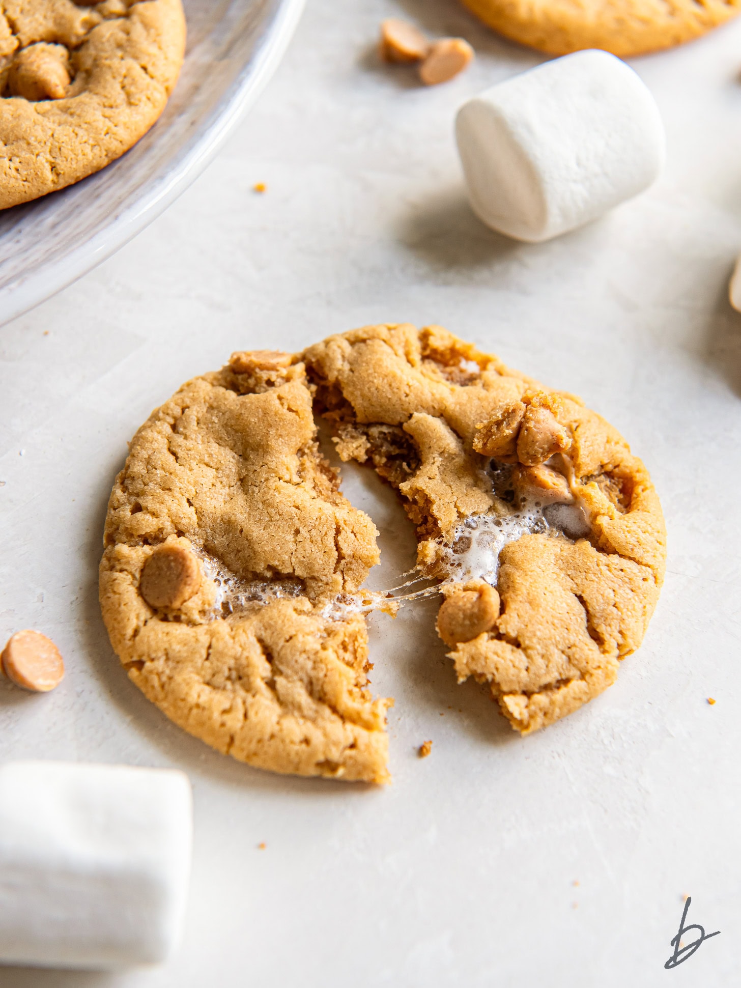 fluffernutter cookie pulled in half with gooey marshmallow and set on a tabletop surface.