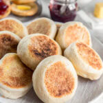 Homemade English muffins stacked on a plate.