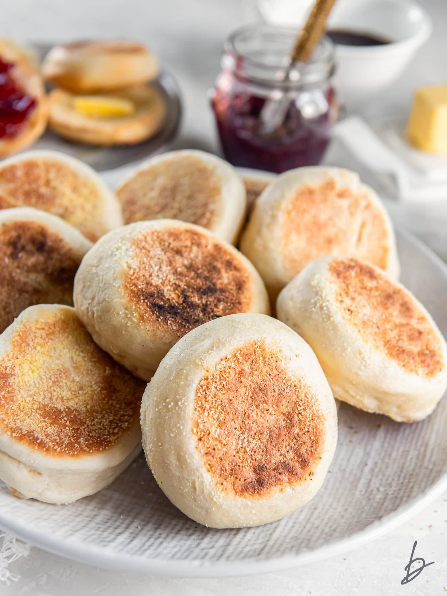 Homemade English muffins stacked on a plate.