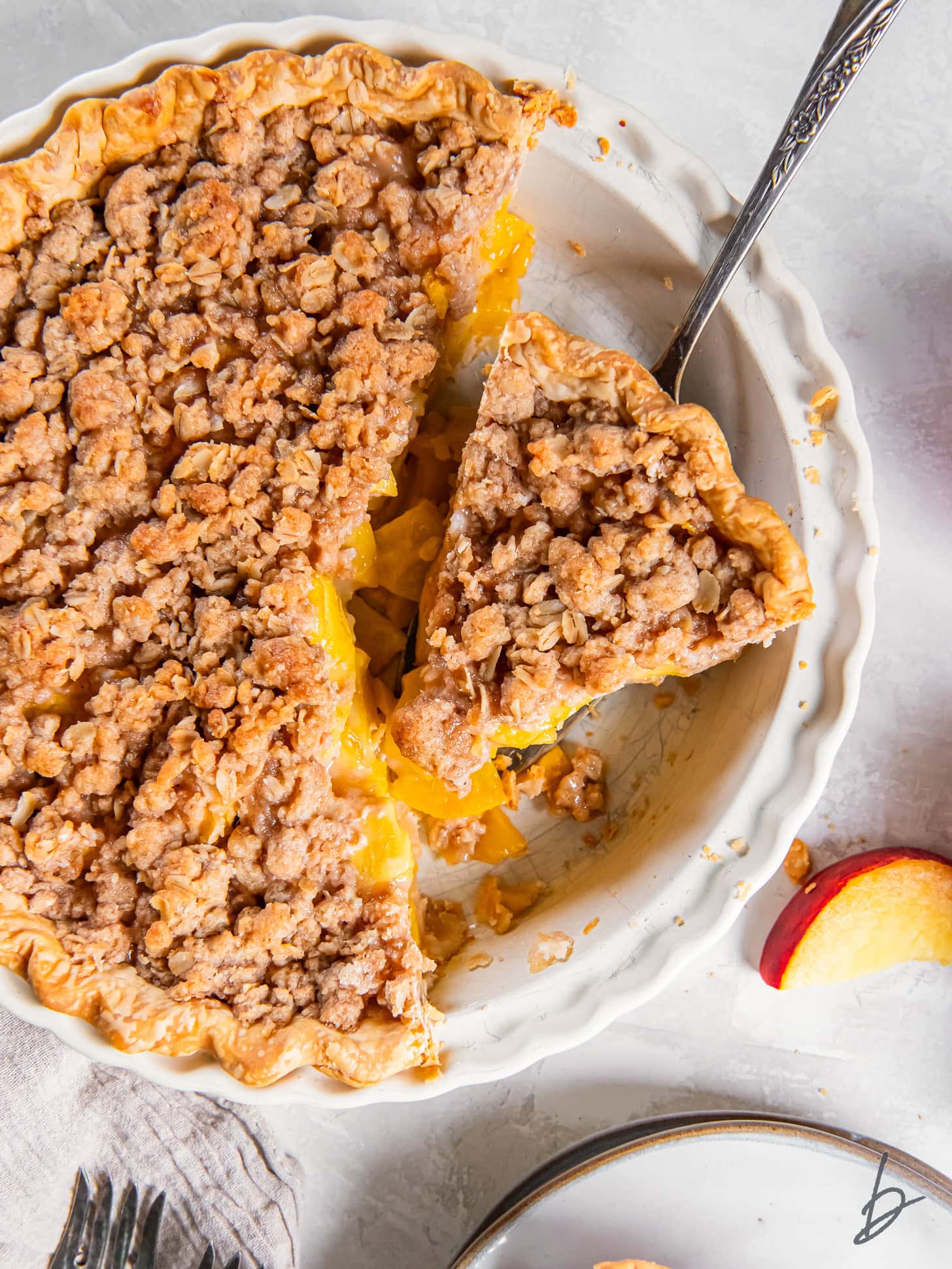 Serving a peach crumble pie out of a pie dish.