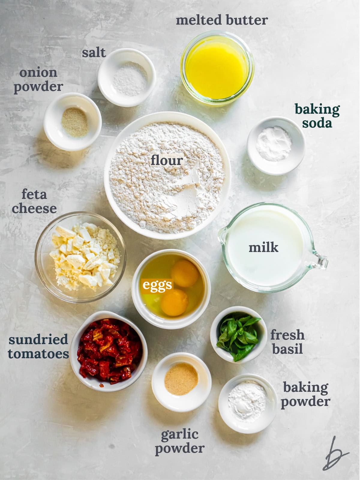 Bowls with flour, butter, seasonings, feta, eggs, sun-dried tomatoes and herbs.