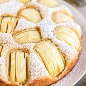 German apple cake topped with a dusting of powdered sugar.