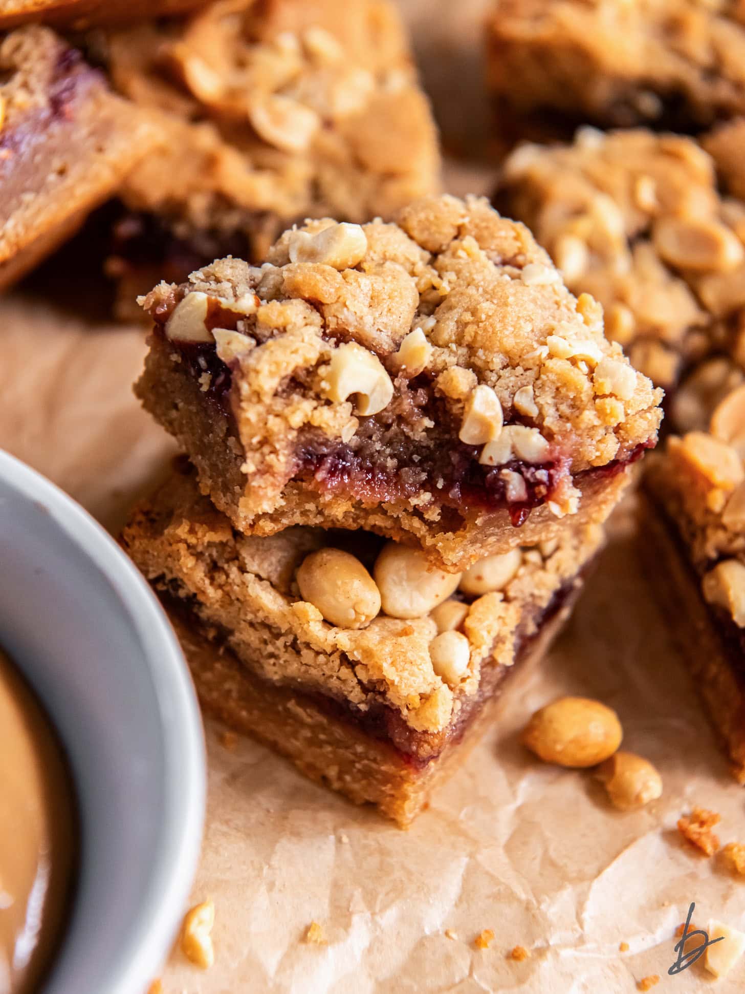 peanut butter jelly bars with a bite sitting on top of another bar.