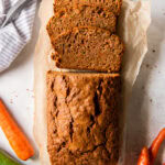 tabletop with loaf of zucchini carrot bread with three slices cut off the end.