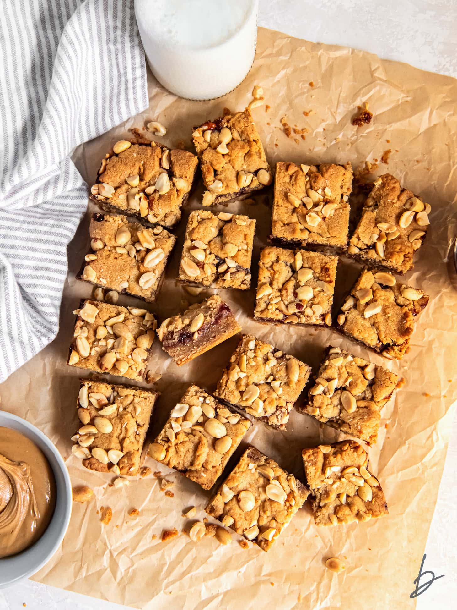 peanut butter and jelly bars cut into squares on parchment paper on tabletop.