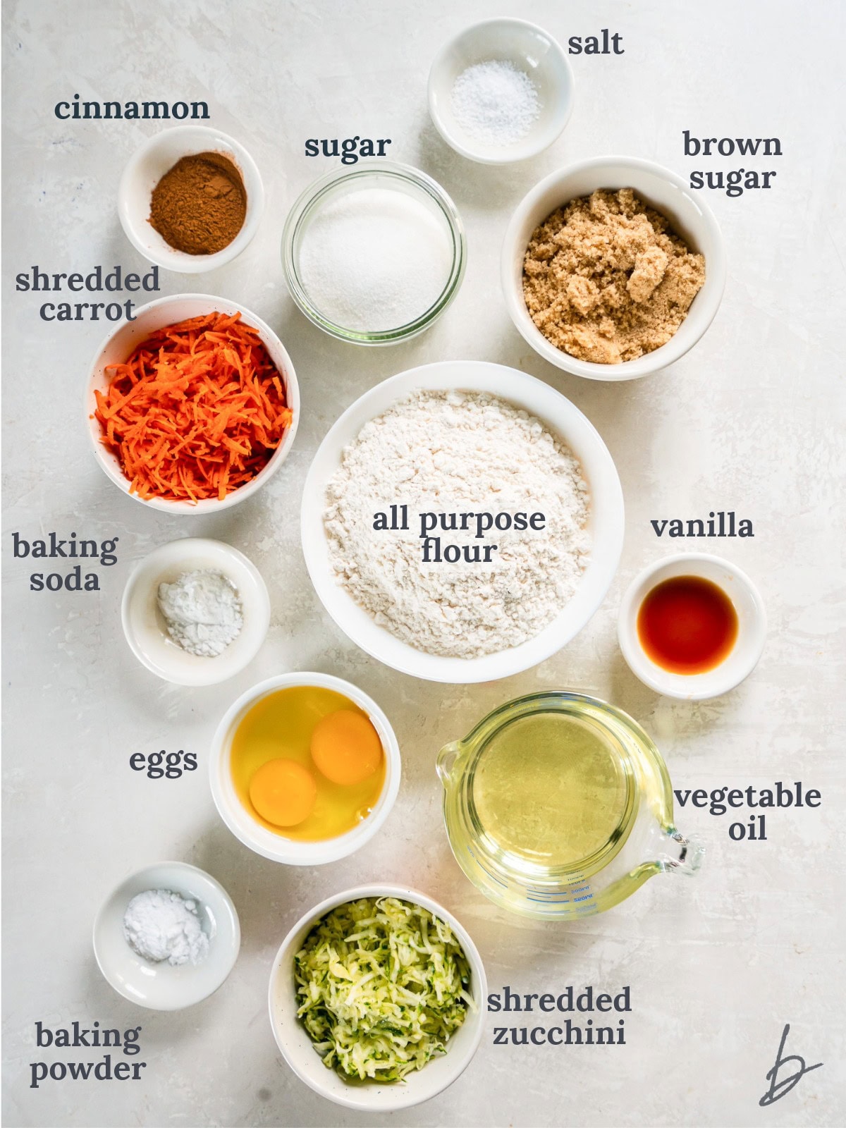 tabletop with bowls of ingredients to make zucchini carrot bread.