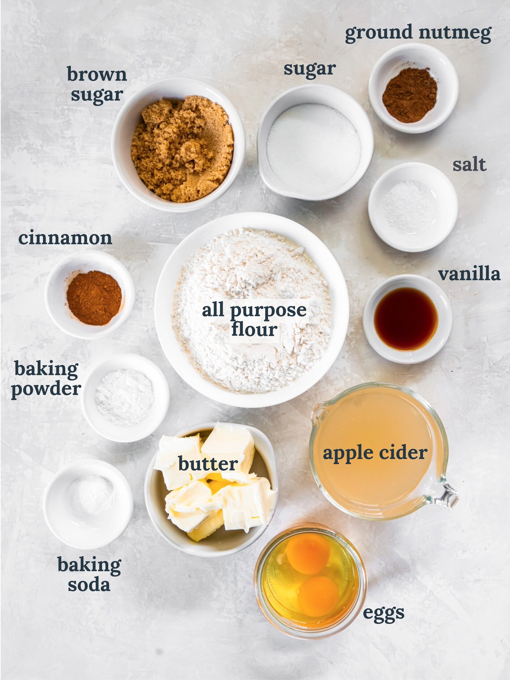 tabletop with bowls of ingredients to make baked apple cider donuts.