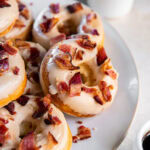 Baked maple bacon donuts on a white plate served with coffee.