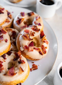 Baked maple bacon donuts on a white plate served with coffee.