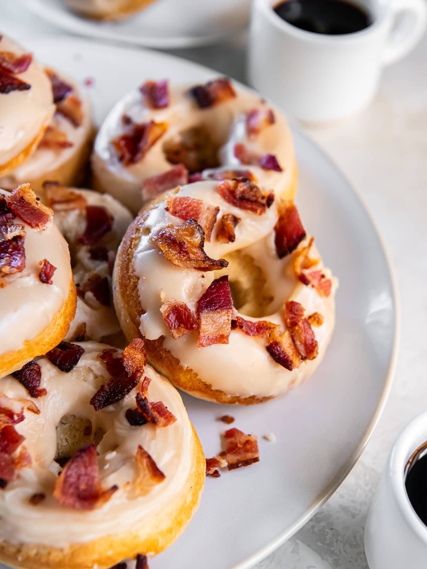 Baked maple bacon donuts on a white plate served with coffee. 