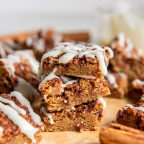 stack of three cinnamon roll blondies in front of more blondies.