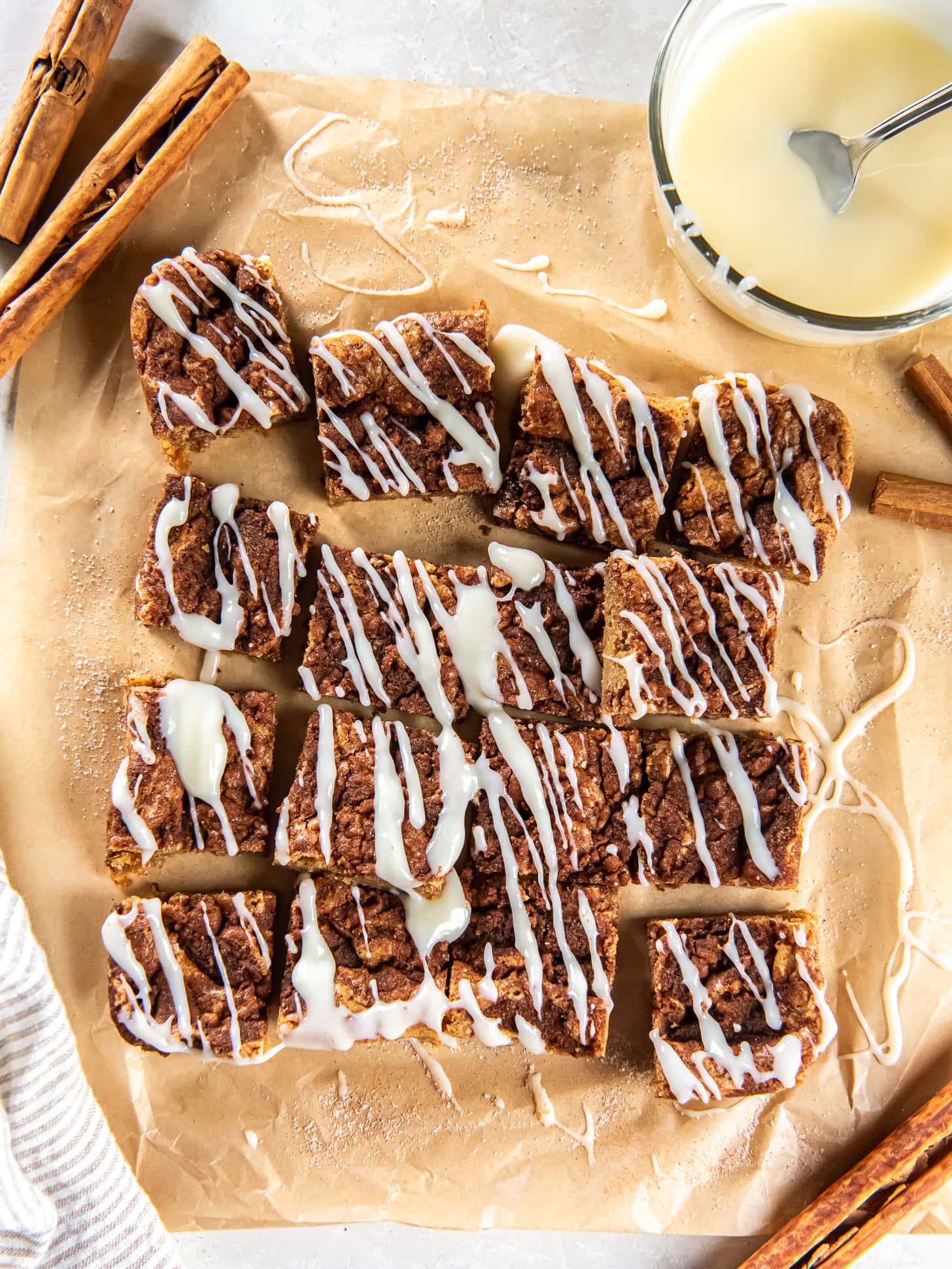 tabletop with cinnamon rolled blondies topped with cream cheese icing cut into squares.
