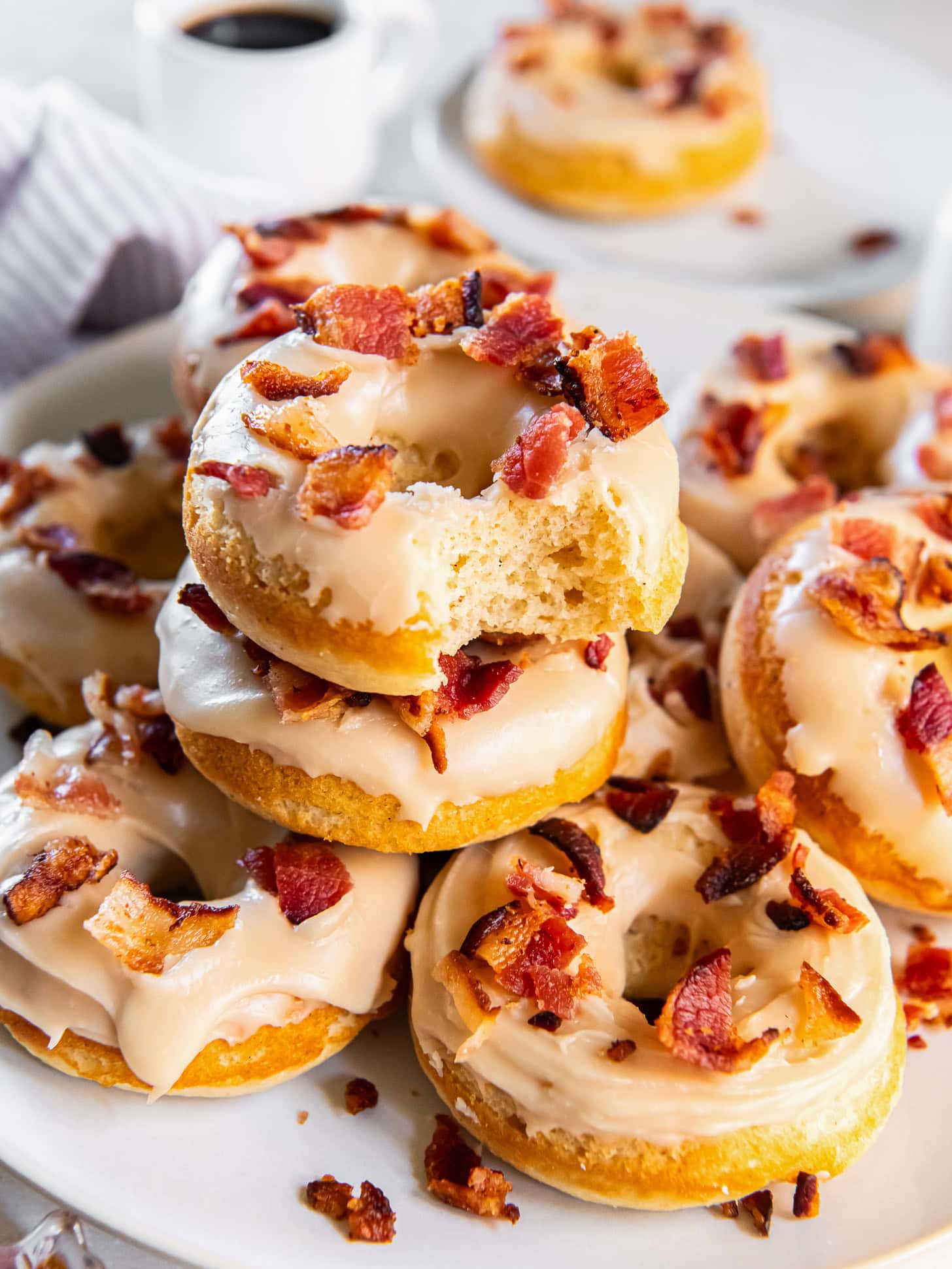 Stacked maple donuts with a bite out of one.