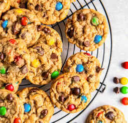 Monster cookies on a round wire cooling rack on tabletop.