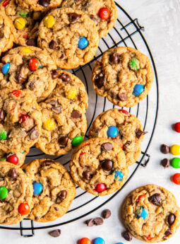 Monster cookies on a round wire cooling rack on tabletop.