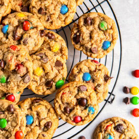 Monster cookies on a round wire cooling rack on tabletop.