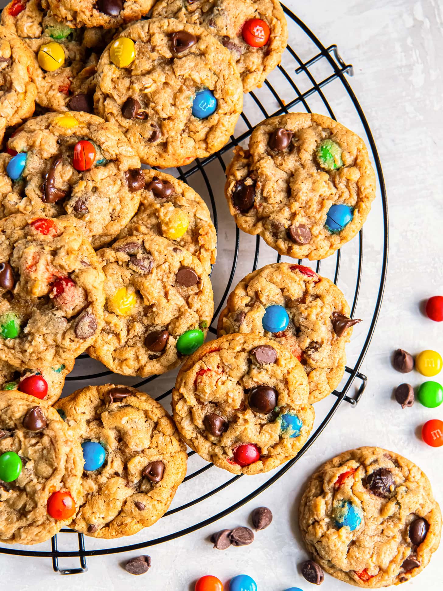 Monster cookies on a round wire cooling rack on tabletop.