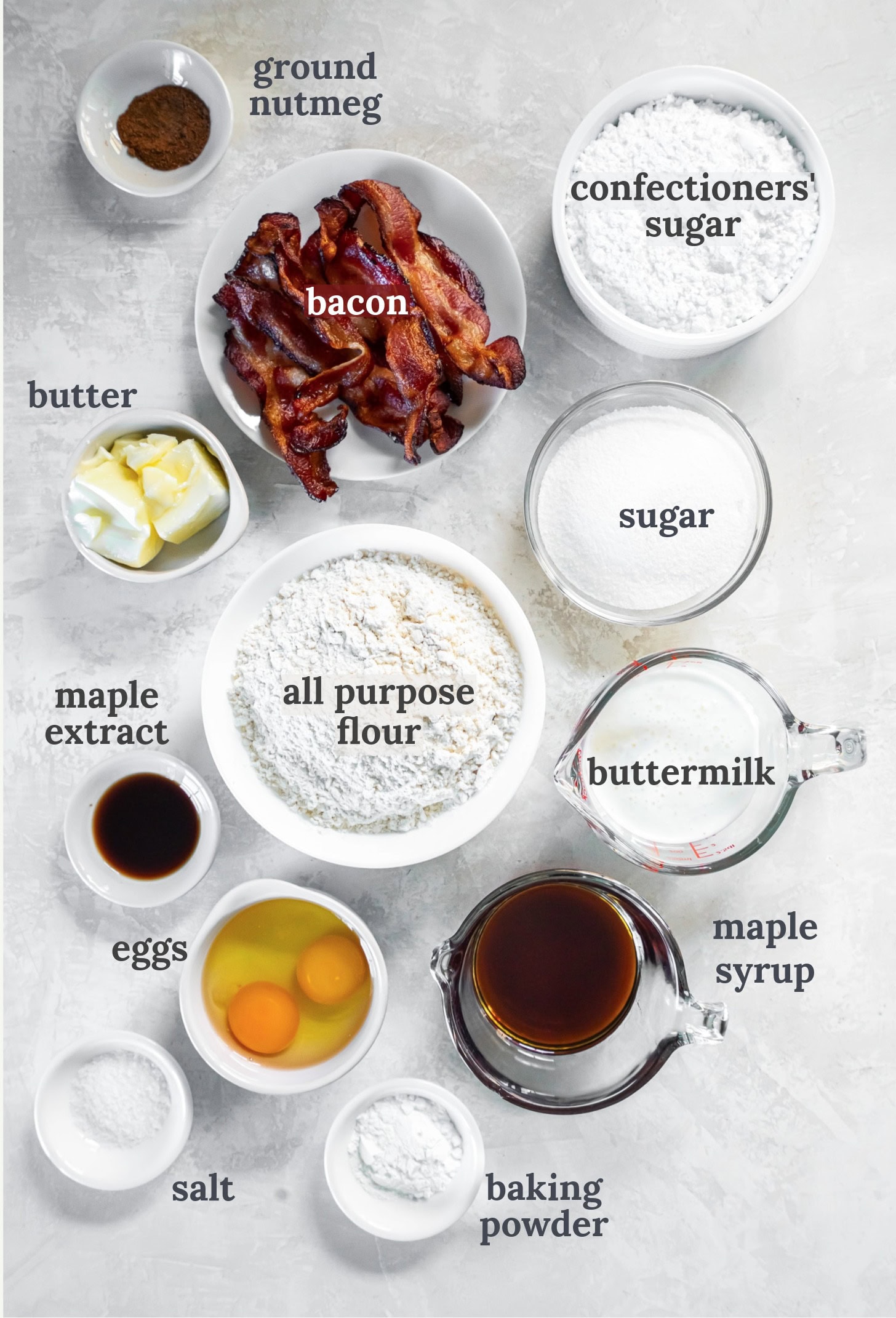 Small bowls with flour, eggs, butter, sugar, maple syrup, bacon and buttermilk.