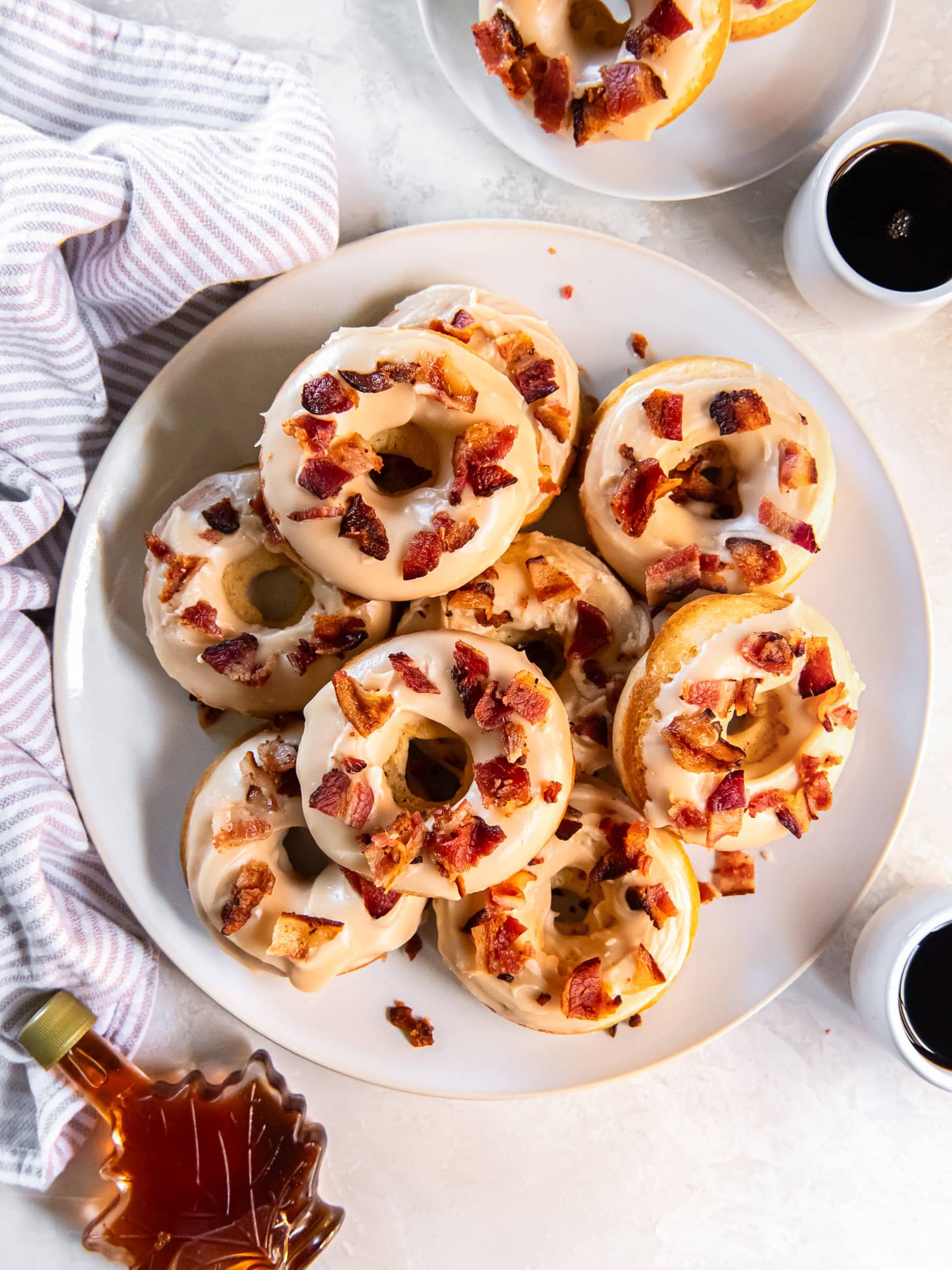 A white plate with stacked maple bacon donuts.