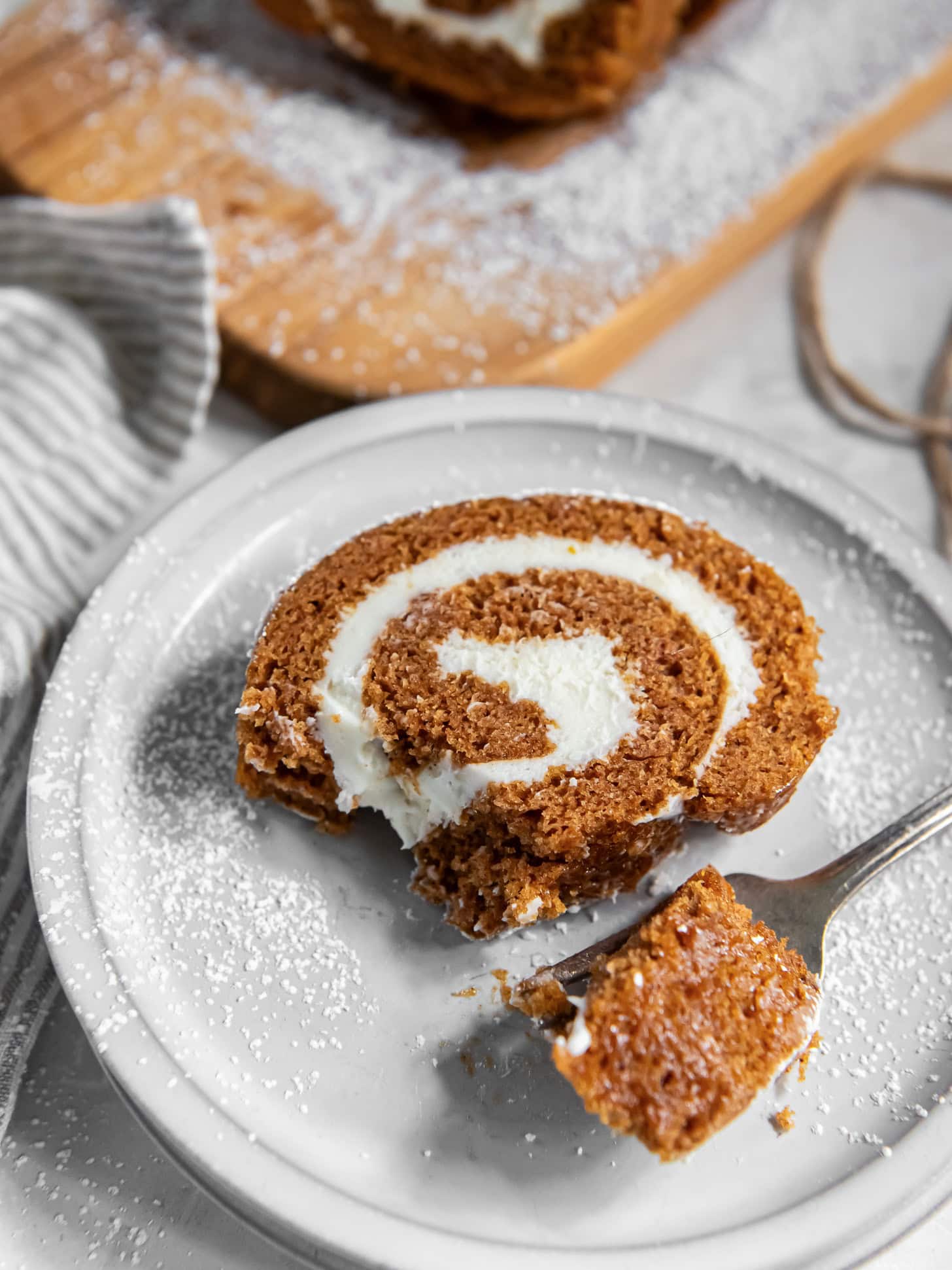 Slice of pumpkin roll on a plate with a forkful.