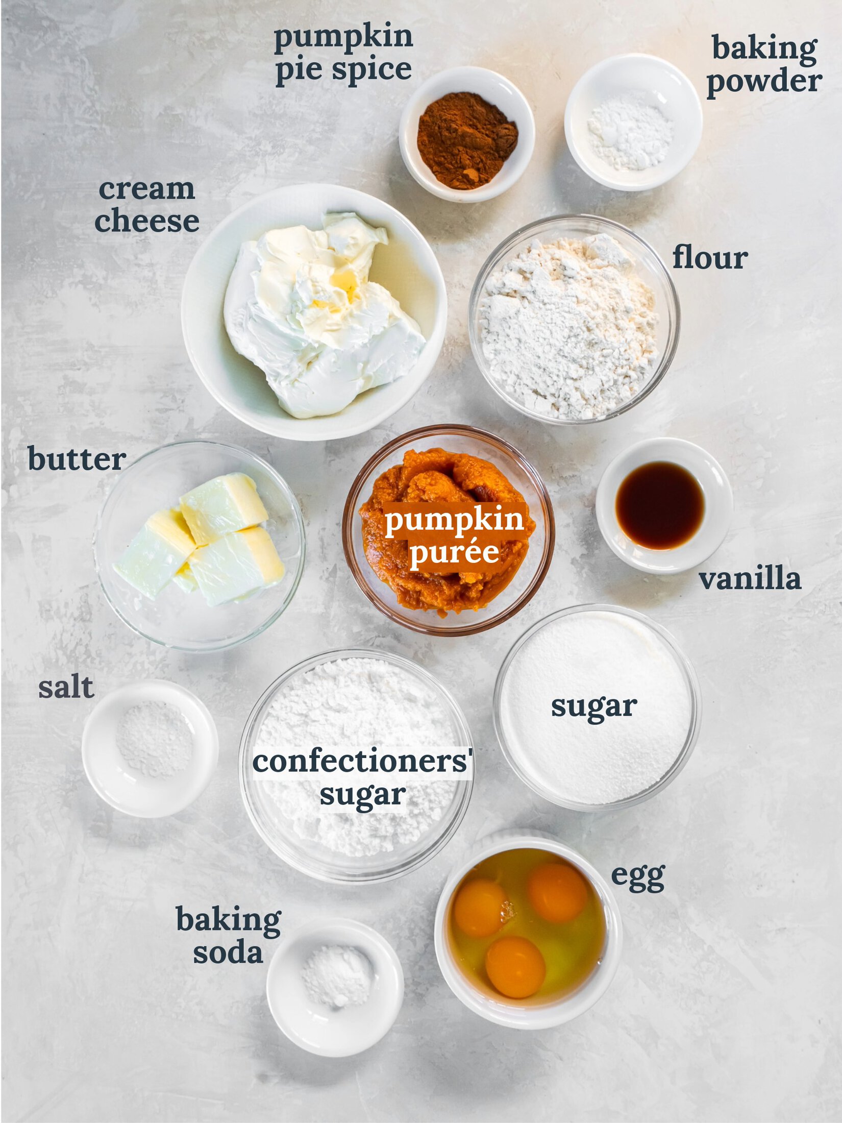 tabletop with bowls of ingredients to make pumpkin roll cake with cream cheese filling.