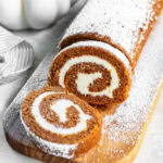 Sliced pumpkin roll cake dusted with powdered sugar.