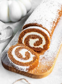 Sliced pumpkin roll cake dusted with powdered sugar.