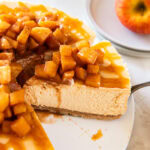 Caramel apple cheesecake being served from a white cake plate.