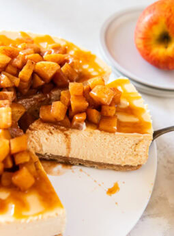 Caramel apple cheesecake being served from a white cake plate.